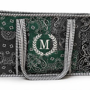 May include: A rectangular tote bag featuring a dark green and black paisley patchwork pattern. The bag has black and white striped trim and handles, with a white embroidered letter M centered inside a laurel wreath on the front panel.