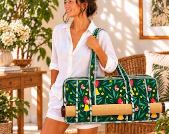 May include: A rectangular green yoga mat bag featuring a repeating pattern of stylized red and yellow birds, small yellow flowers, and green leaves. The bag has white and green striped trim, two shoulder straps, and a bamboo mat inside.