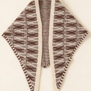 May include: A brown and cream-colored knitted shawl with a geometric pattern. The shawl has a triangular shape with a cream-colored border and a vertical opening in the center.