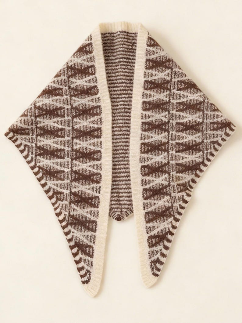 May include: A brown and cream-colored knitted shawl with a geometric pattern. The shawl has a triangular shape with a cream-colored border and a vertical opening in the center.