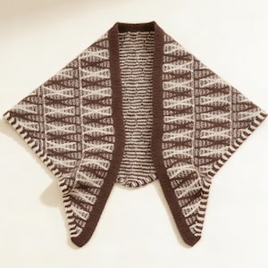 May include: A brown and cream-colored knitted shawl with a geometric pattern. The shawl has a dark brown border and a unique open front design. The pattern features a series of intersecting lines and shapes, creating a textured look. The shawl is made of a soft, warm material.