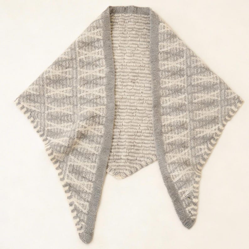 May include: A gray and white knitted shawl with a geometric pattern. The shawl has a triangular shape with a ribbed border and a textured design. The color scheme is neutral, with shades of gray and white, making it a versatile accessory.
