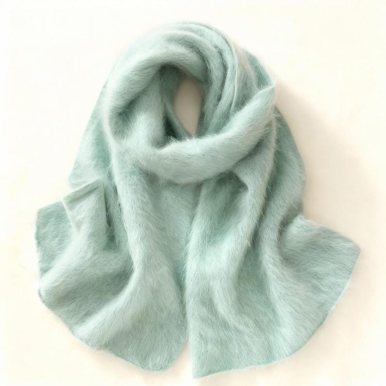 Peut inclure: Une &eacute;charpe bleu clair en mati&egrave;re duveteuse. L'&eacute;charpe est drap&eacute;e et pli&eacute;e, mettant en valeur sa texture et sa couleur. L'&eacute;charpe semble &ecirc;tre faite d'une mati&egrave;re chaude, id&eacute;ale pour les temps froids.