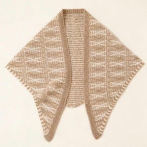 May include: A beige knitted shawl with a geometric pattern in off-white. The shawl has a draped design with a rounded neckline and a textured border. The overall style is cozy and suitable for layering.
