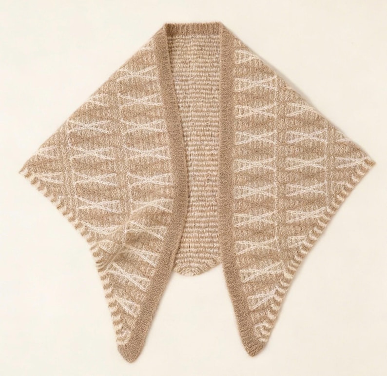 May include: A beige knitted shawl with a geometric pattern in off-white. The shawl has a draped design with a rounded neckline and a textured border. The overall style is cozy and suitable for layering.