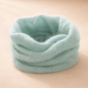 Può includere: Una sciarpa a collo in maglia blu chiaro. La sciarpa è realizzata in un materiale morbido e soffice e presenta una trama a coste. Il collo è progettato per essere indossato intorno al collo per calore e stile. Un accessorio accogliente per il clima freddo.