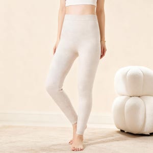 Könnte beinhalten: Cremefarbene Leggings aus weichem Strickmaterial. Die Leggings haben eine hohe Taille und eine enge Passform, ideal zum Überziehen oder Entspannen. Die neutrale Farbe macht sie vielseitig.