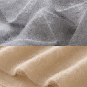 Peut inclure: Gros plan sur deux sections de tissu doux et duveteux. La section sup&eacute;rieure est gris clair et la section inf&eacute;rieure est beige chaud. Le tissu semble &ecirc;tre drap&eacute;, avec des plis et des textures visibles.