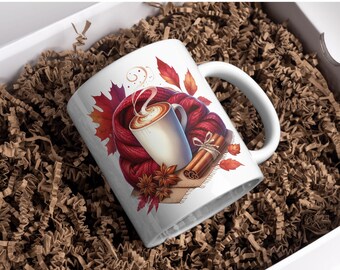 May include: White ceramic mug with a fall-themed design, featuring a cup of coffee, a red scarf, cinnamon sticks, and autumn leaves. The mug is presented in a white gift box with brown paper filler.