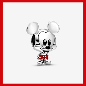 May include: A silver charm featuring Mickey Mouse with large round ears, a smiling face, and red shorts with white polka dots. The charm is a detailed, three-dimensional design.