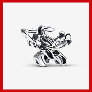 May include: A silver-colored charm featuring a stylized, abstract design. The charm has a three-dimensional appearance with curved lines and a smooth, reflective surface. The charm is likely made of metal and is designed to be attached to a bracelet or necklace.