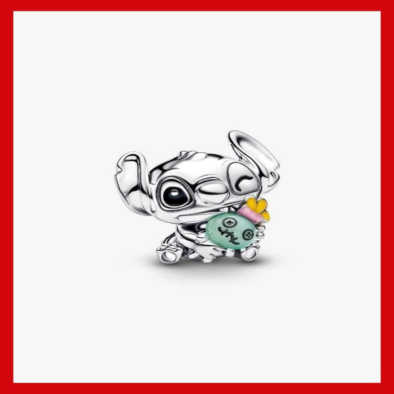 Puede incluir: Un charm de plata que representa al personaje Stitch de Lilo & Stitch. Stitch gui&ntilde;a un ojo y sostiene un objeto verde y rosa con una mariposa amarilla. El charm es detallado y tiene un acabado pulido.