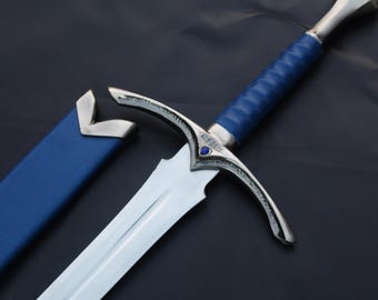 May include: A silver and blue sword with a blue handle and a matching blue sheath. The sword has a curved crossguard with a small blue gem. The blade is silver and the sheath is lying next to the sword.
