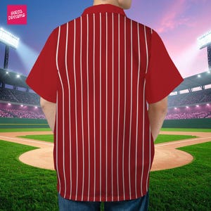 K&ouml;nnte beinhalten: Rot-wei&szlig; gestreiftes Hemd mit kurzen &Auml;rmeln und klassischem Kragen. Das Hemd hat vertikale wei&szlig;e Streifen auf rotem Grund. Das Hemd hat den Text "Herza Dreams" in einer rosa Box.