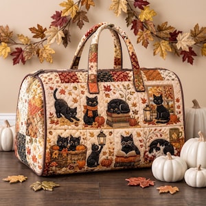 Op de afbeelding: Een gewatteerde reistas met een patchworkpatroon van zwarte katten, herfstbladeren, pompoenen en boeken. De tas heeft twee handvatten, een ritssluiting en een crèmekleurige achtergrond met herfstachtige accenten in oranje, bruin en goud.