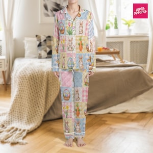 Puede incluir: Un conjunto de pijama patchwork con diseños de Pascua. El conjunto incluye una camisa con botones y pantalones, con cuadrados de colores pastel, conejitos, huevos, zanahorias y estampados florales. El pijama tiene ribetes blancos y el texto "Herza Dreams" es visible.