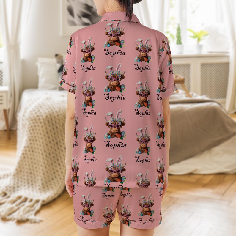 May include: Pink pajama set featuring a repeating pattern of a cartoon cow wearing sunglasses and bunny ears, with the name "Sophia" below each image. The set includes a short-sleeved top and shorts.