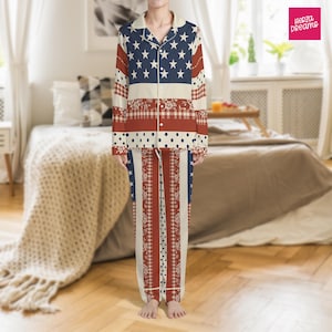 Peut inclure: Un ensemble de pyjama deux pièces au design patriotique. Le haut est une chemise boutonnée avec un panneau bleu étoilé, des rayures rouges et blanches, et des motifs floraux et à pois. Le pantalon assorti a un design similaire. La marque "Herza Dreams" est en haut à droite.