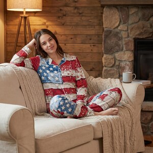 May include: A person wearing a patchwork pajama set with a design inspired by the American flag, including red, white, and blue colors. The pajamas have a button-down top and matching pants. The person is sitting on a beige couch.