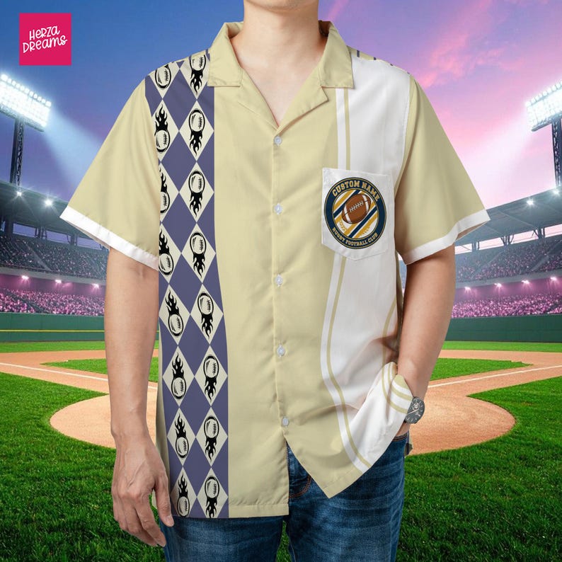 K&ouml;nnte beinhalten: Ein kurz&auml;rmeliges Button-Down-Shirt mit Football-Motiv. Das Shirt hat eine cremefarbene Basis mit einem vertikalen Panel aus blauen Rauten und Football-Grafiken. Eine Tasche zeigt ein Football-Club-Logo. Das Shirt hat den Text "Herza Dreams".