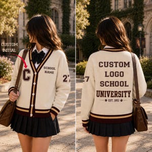 May include: A cream-colored V-neck cardigan with maroon and gold striped trim. The front features a custom initial C, the text SCHOOL NAME, and the number 27 on the sleeve. The back displays CUSTOM LOGO SCHOOL UNIVERSITY EST. 1851.