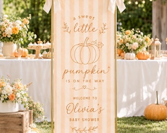 May include: A tall, rectangular vertical banner with light orange and white vertical stripes, featuring a central pumpkin illustration and the text: A sweet little pumpkin is on the way, Welcome to Olivia's Baby Shower. It has cream bows at the top.