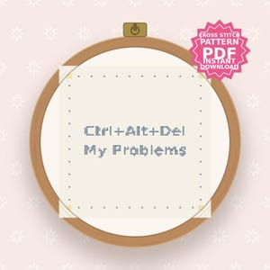 May include: A round wooden embroidery hoop containing white fabric with a cross-stitch design. The text reads Ctrl+Alt+Del My Problems in dark blue thread. A pink star-shaped badge in the top right corner states Cross Stitch Pattern PDF Instant Download.