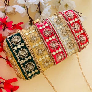May include: A rectangular clutch with a gold chain strap. The clutch is divided into vertical sections of green, gold, red, and silver, each adorned with intricate gold embroidery. The floral and geometric patterns are highlighted with gold trim.