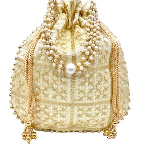 Può includere: Un sacchetto dorato con coulisse, ricami intricati e un accento di perla. La borsa presenta un cinturino di perline e dettagli a nappe. Il sacchetto è realizzato in un tessuto strutturato con un motivo geometrico.