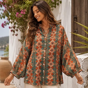 Può includere: Una camicia a maniche lunghe con bottoni caratterizzata da un motivo geometrico a rombi nei toni dell'arancione ruggine, verde ottanio e crema. La camicia presenta un colletto alla coreana, maniche ampie con polsini e un design a righe verticali.