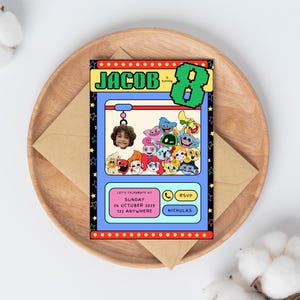 Könnte beinhalten: Eine Geburtstagseinladung mit einem Greifautomaten-Design, die den Namen "JACOB" und die Zahl "8" zeigt. Die Einladung enthält den Text "LET'S CELEBRATE AT" und RSVP-Details. Sie liegt auf einem Holztablett mit einem braunen Umschlag.