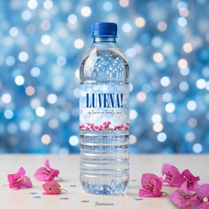 Könnte beinhalten: Eine transparente Plastikwasserflasche mit blauem Deckel und einem Etikett mit der Aufschrift "LUVENA! is turning twenty six." Das Etikett hat einen himmelblauen Hintergrund mit rosa Blumen. Rosa Blüten und sternförmige Konfetti sind um die Flasche verstreut.