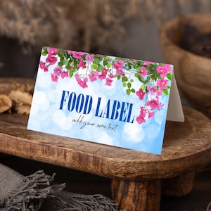 May include: A folded food label with a blue background and the words "FOOD LABEL" in dark blue. Pink flowers and green leaves decorate the top. The text "add your own text" is below the main text.