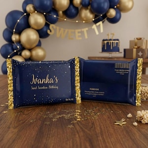 May include: Two navy blue candy bar wrappers with gold glitter edges and text that reads "Ivanka's Sweet Seventeen Birthday." The wrappers are on a wooden surface with gold star confetti. A navy blue cake with gold icing is in the background.