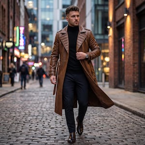 May include: A long brown leather trench coat with wide lapels and belted cuffs, worn over a black turtleneck sweater and dark trousers. The coat features structured shoulders and a buttoned front closure, paired with dark brown leather boots.