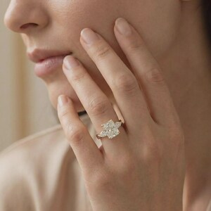 Radiant three-stone pear diamond ring by ExcellentJewels featuring an elegant engagement design in custom gold. This timeless fine jewelry piece showcases a pear-shaped center diamond flanked by two sparkling side stones for maximum brilliance. Perfect for engagements, anniversaries, or special occasions, it combines sophisticated design with classic elegance, creating a luxurious and unforgettable statement ring.