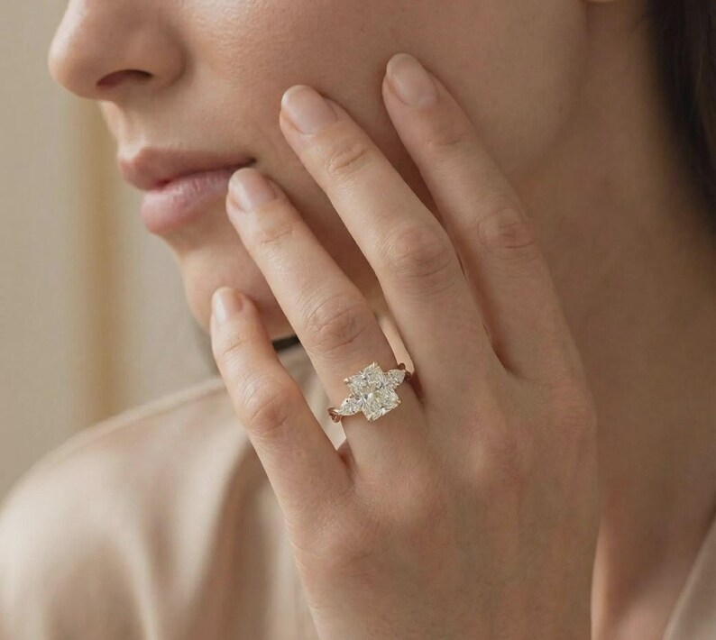 Radiant three-stone pear diamond ring by ExcellentJewels featuring an elegant engagement design in custom gold. This timeless fine jewelry piece showcases a pear-shaped center diamond flanked by two sparkling side stones for maximum brilliance. Perfect for engagements, anniversaries, or special occasions, it combines sophisticated design with classic elegance, creating a luxurious and unforgettable statement ring.