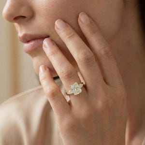 Radiant pear-shaped diamond trio ring from ExcellentJewels. Customizable engagement ring with classic three-stone design symbolizing past, present, and future. Handcrafted for comfort, brilliance, and style. Elegant fine jewelry suitable for daily wear, proposals, or gifting to a loved one for special occasions. Handcrafted gold vine band ring with radiant cut diamond and pear diamonds.