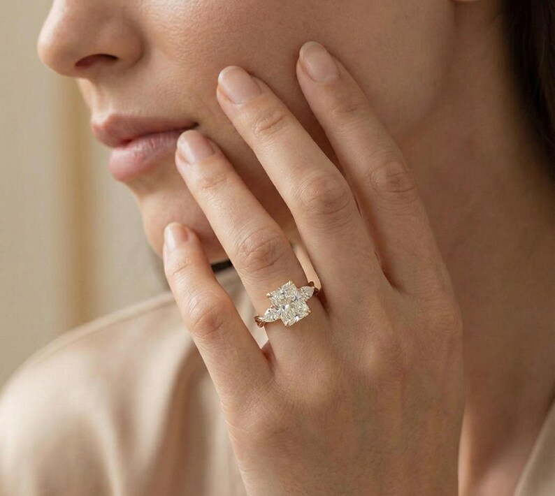 Radiant pear-shaped diamond trio ring from ExcellentJewels. Customizable engagement ring with classic three-stone design symbolizing past, present, and future. Handcrafted for comfort, brilliance, and style. Elegant fine jewelry suitable for daily wear, proposals, or gifting to a loved one for special occasions. Handcrafted gold vine band ring with radiant cut diamond and pear diamonds.
