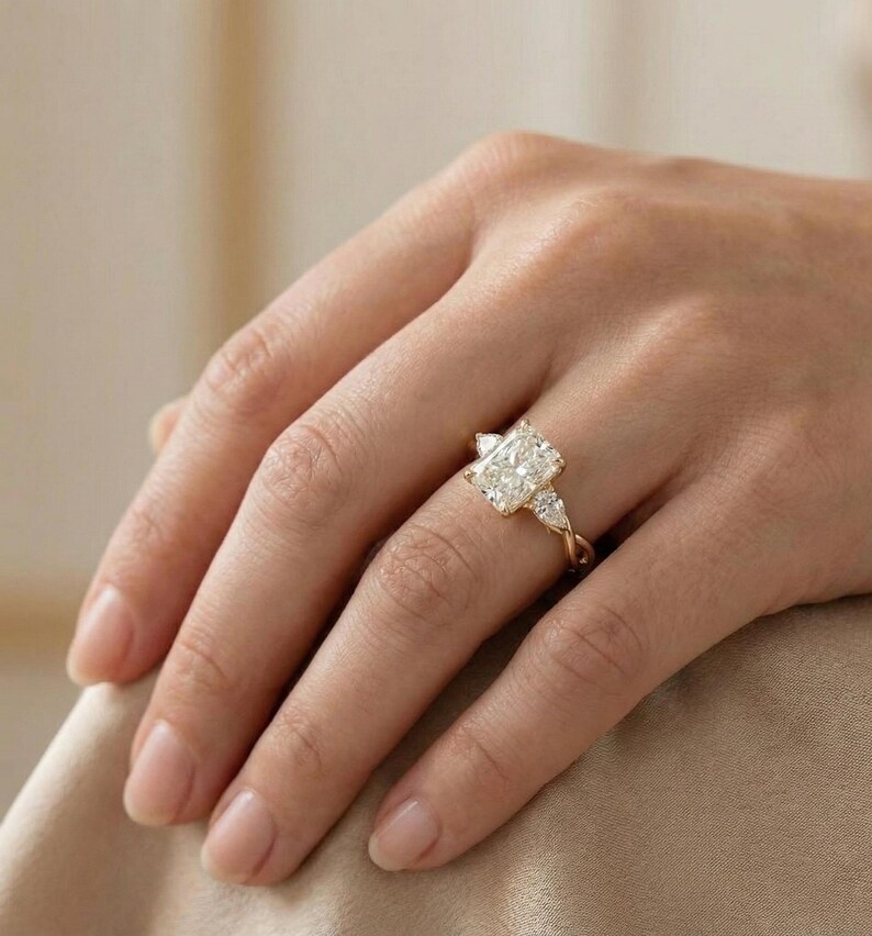 Three-stone pear diamond radiant ring by ExcellentJewels, ideal engagement or anniversary piece. Handcrafted fine jewelry with elegance, durability, and customizable features. Timeless design suitable for special occasions or everyday wear. A meaningful, sparkling gift for couples or anyone seeking high-quality diamond jewelry. Nature themed gold diamond ring with radiant center stone and pear accents.