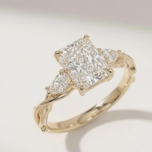 Radiant pear diamond three-stone ring from ExcellentJewels, crafted in custom gold for an elegant and timeless look. The central pear-cut diamond is accentuated by two side stones, creating a sophisticated engagement ring perfect for celebrating love, milestones, or special occasions with luxurious fine jewelry style.