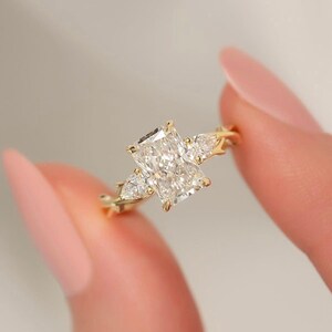Three-stone pear diamond ring by ExcellentJewels, radiant cut for exceptional sparkle. Handcrafted engagement or statement ring with customizable options. Elegant, timeless design suitable for weddings, anniversaries, or personal collection. Perfect gift for couples or jewelry enthusiasts seeking meaningful and sophisticated fine jewelry. Radiant solitaire engagement ring with leaf design shank and pear diamonds.
