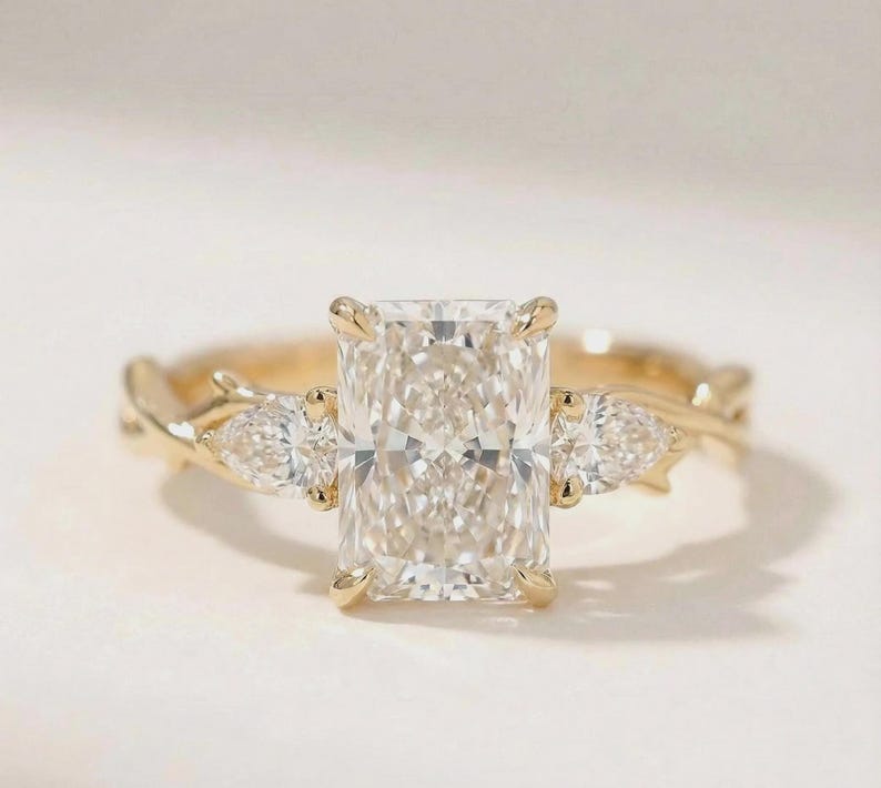 Elegant three-stone pear diamond engagement ring by ExcellentJewels, featuring a radiant center diamond and two accent stones in a custom gold setting. This fine jewelry piece offers timeless beauty, sparkling brilliance, and sophisticated design, making it perfect for proposals, anniversaries, or as a luxurious gift for someone special.