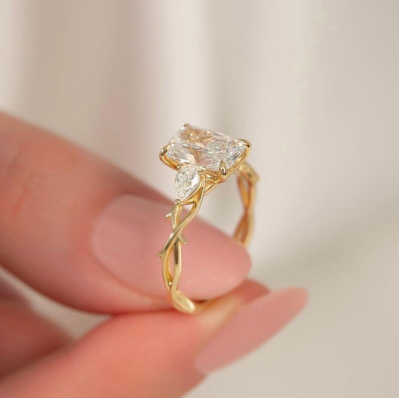 Radiant pear diamond trio ring by ExcellentJewels, expertly handcrafted for engagement or special occasions. Timeless three-stone design symbolizing love and commitment. Customizable for personal style and metal choice. Elegant, durable, and sparkling fine jewelry piece suitable for gifting or daily wear. Yellow gold engagement ring featuring radiant diamond and pear side stones.