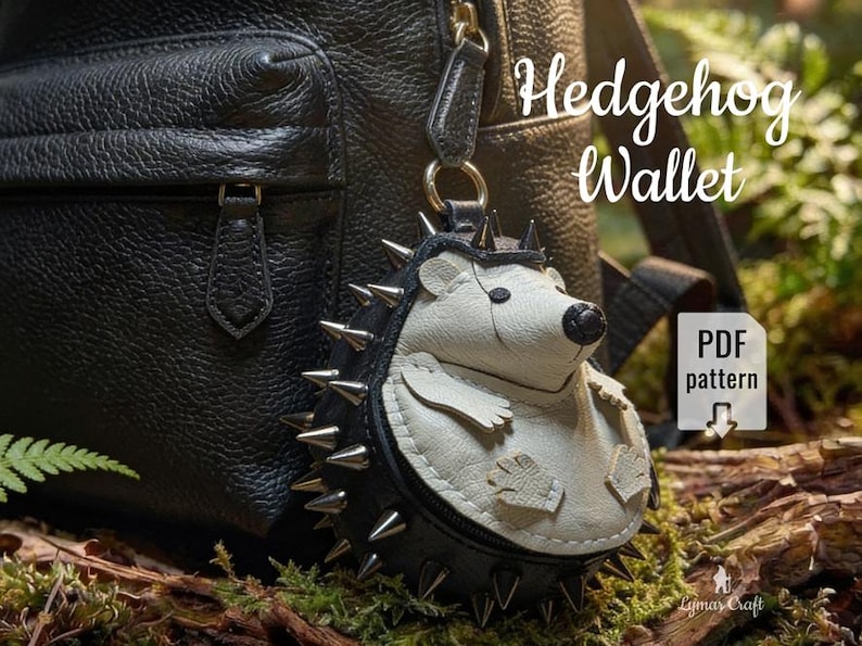 May include: A hedgehog-shaped wallet with a black and white design, featuring silver spikes around the body. The wallet is hanging from a black leather backpack. Text on the image reads "Hedgehog Wallet" and "PDF pattern".