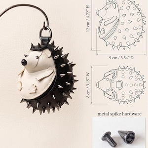 May include: A black and white hedgehog-shaped accessory with metal spike hardware. The accessory is 4.72 inches high, 3.54 inches in diameter, and 3.15 inches wide. The design includes a top loop for hanging.