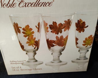 May include: A product box for Noble Excellence Falling Leaves handpainted beverage glasses. The box displays three clear glasses with orange, yellow, and brown leaf patterns, labelled as a set of four 532 ml glasses.