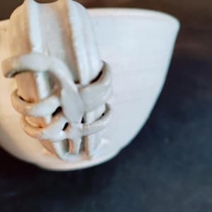 May include: White ceramic mug with a unique, textured handle. The handle is shaped like a twisted rope and has a smooth, white finish.