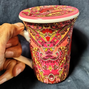 Barnes & Noble Punctuate porcelain tea cup features a vibrant pink and burgundy paisley design and comes with a matching lid
