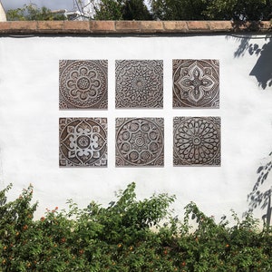 May include: Six square wall tiles with intricate, carved, mandala-like designs in shades of brown and white.